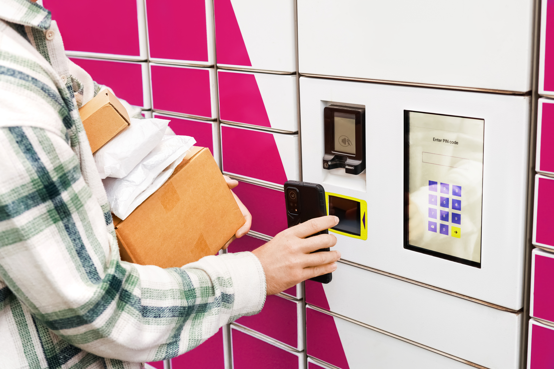 Smart Parcel Lockers and Self-Service Package Pickup Customer using a smartphone at a smart parcel locker terminal while collecting packages from an automated pickup station